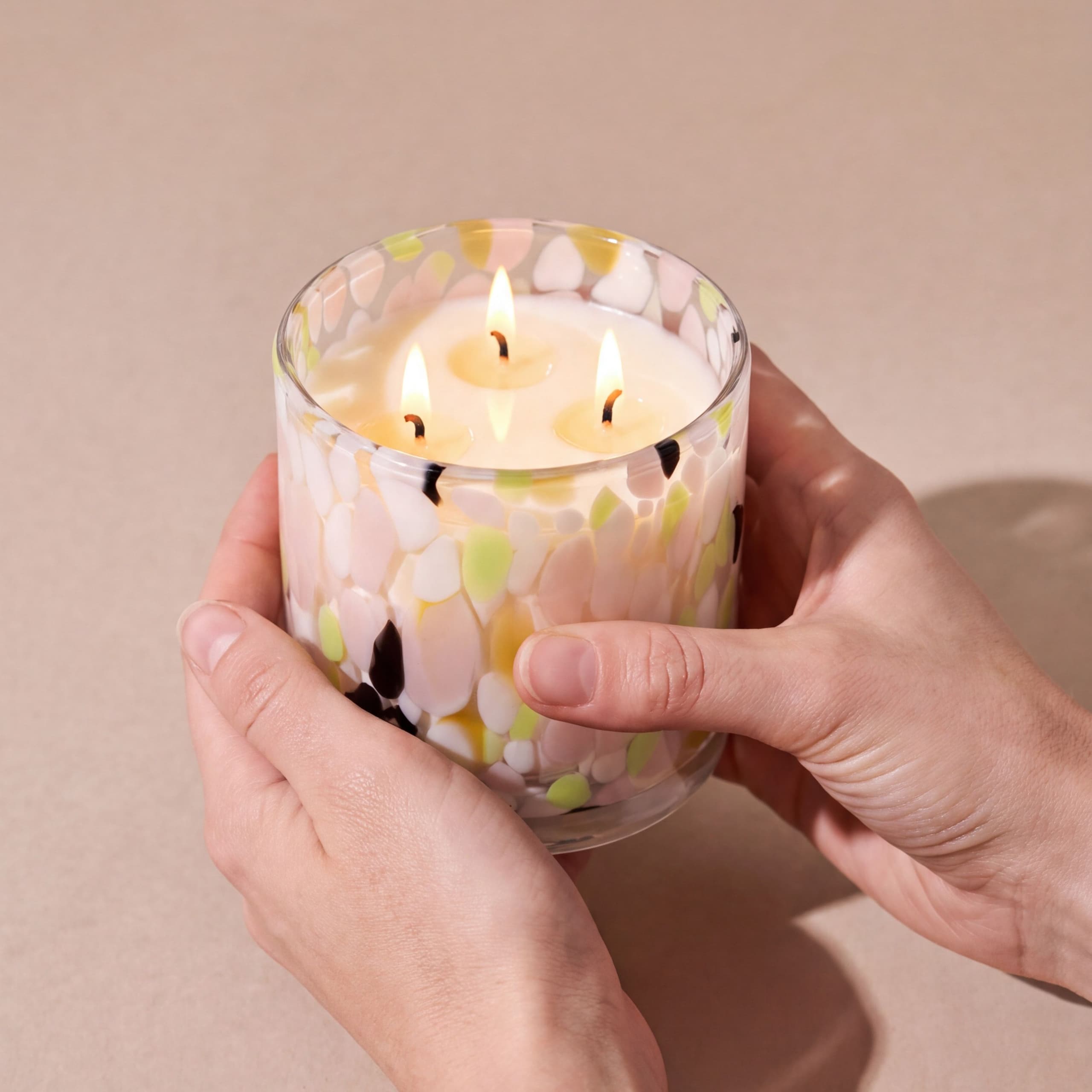 The Happiness Candle, lit and held in two hands to show its size